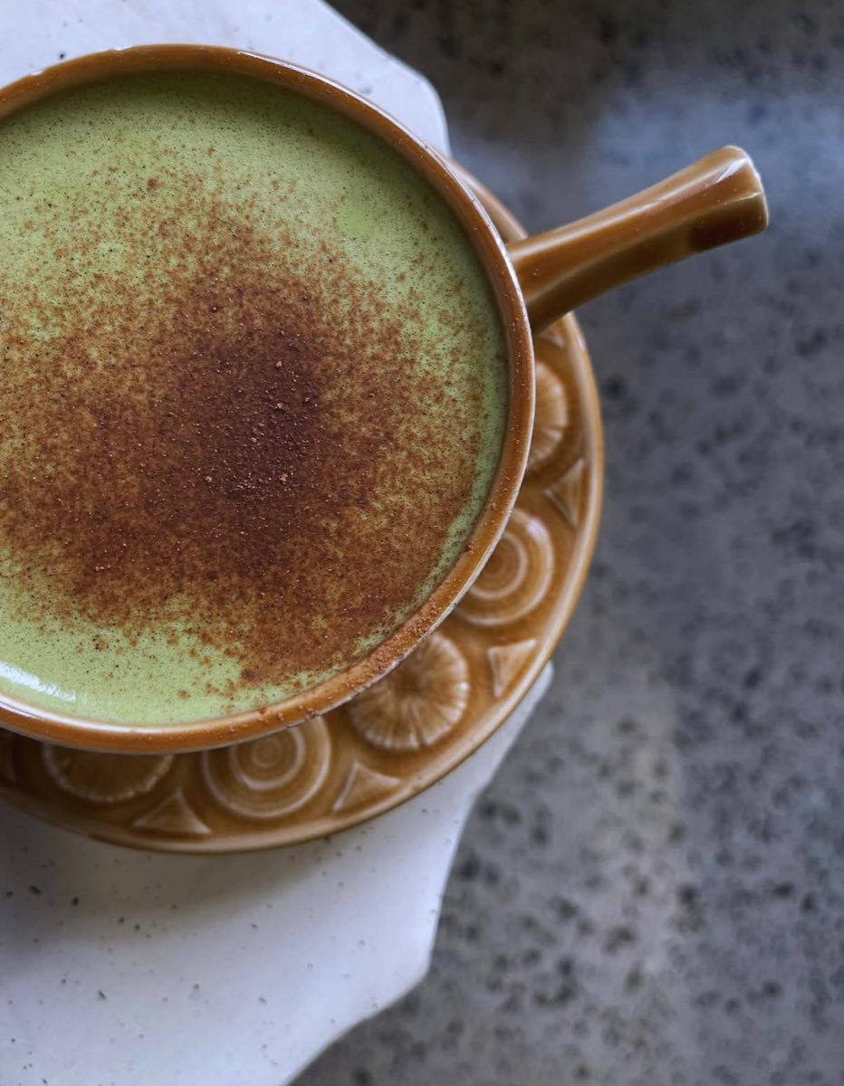 A turmeric latte dusted with cinnamon in a glazed ceramic cup