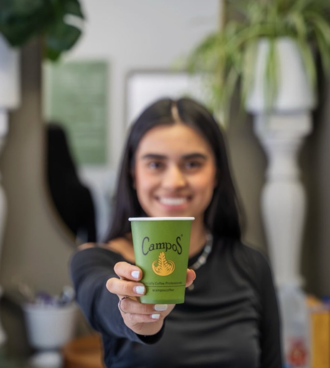 A guest holding out a Campos coffee in the cafe at Ark
