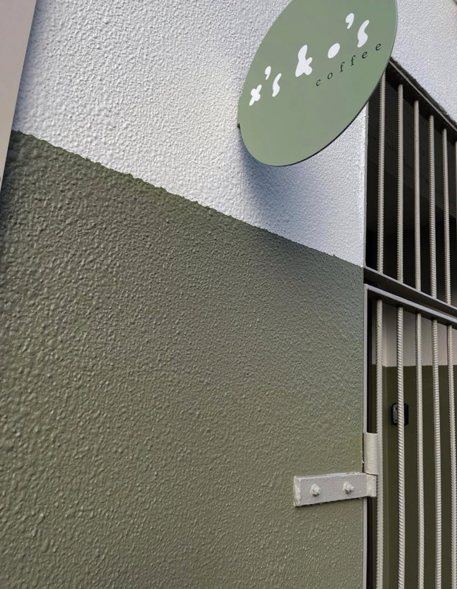 The round X's + O's coffee sign on the olive-green wall outside