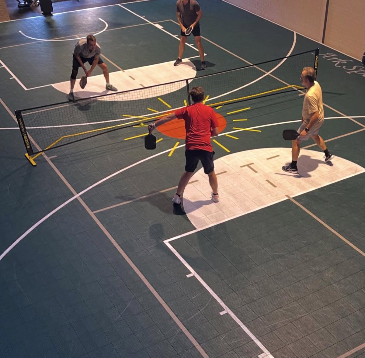 Four players mid-rally on the pickleball court at Ark