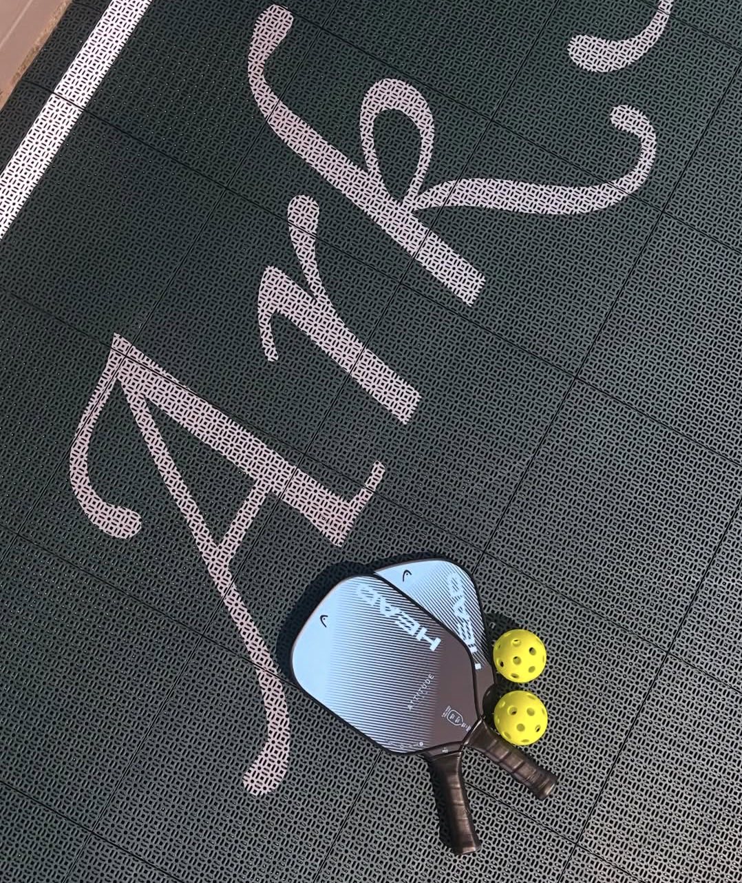 Two pickleball paddles and balls resting on the Ark court