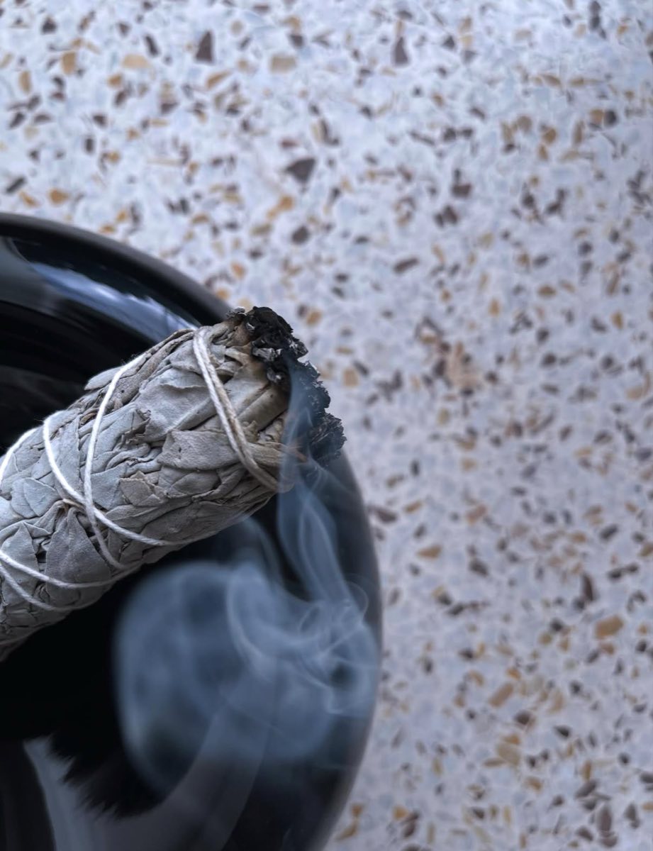 A smudge stick smoking gently on a terrazzo bench